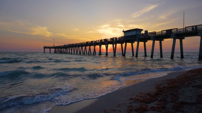 佛罗里达威尼斯捕鱼码头沙滩上田园诗般的日落。傍晚的海景，海浪拍打着覆盖着马尾藻的海岸