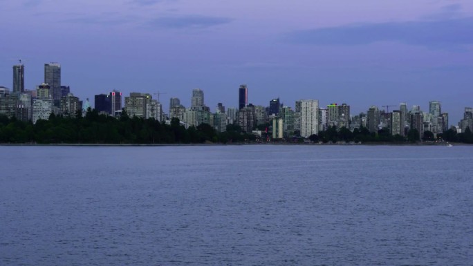 城市在海岸线的平移镜头。平静的水面和远处的高楼大厦