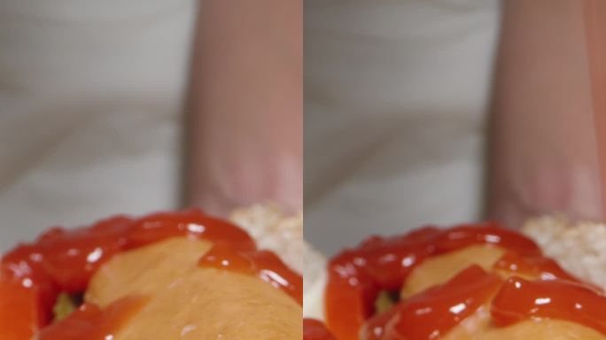 穿白衣的女人把番茄酱倒在黑色背景的热狗上。多莉滑块极端特写。垂直视频。