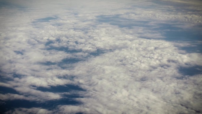 从飞机窗口鸟瞰地球。在地球上空飞行的飞机上，以电影般的慢动作俯视着大西洋上空蓬松的风暴云。