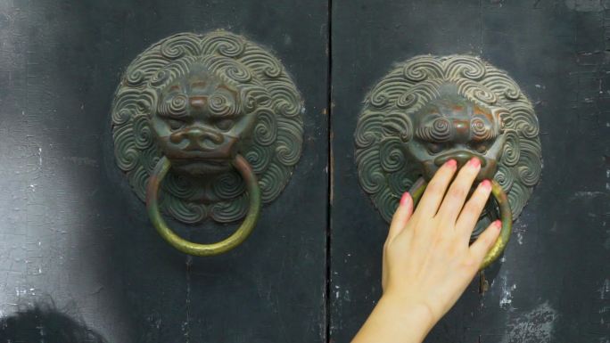 女孩用手抚摸老式木门上的铜环