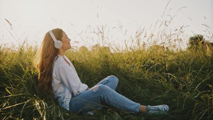 日落时分，一名女子在田野里欣赏音乐