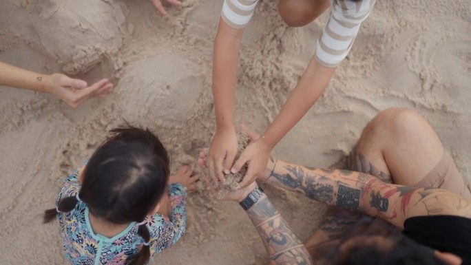夏日周末，一家人在日落时分一起建造沙滩沙堡