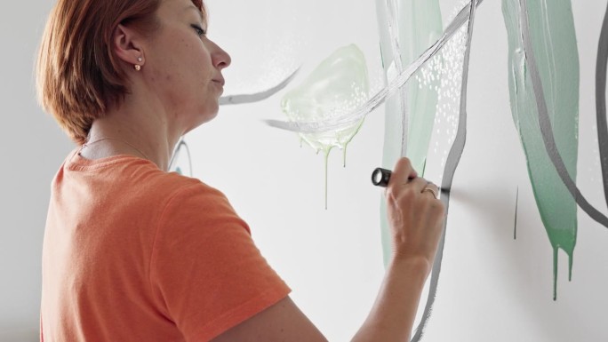 用记号笔线条艺术壁画。成熟的红发女人用水彩笔在墙上画画。镜头与拉平移上升艺术相机运动