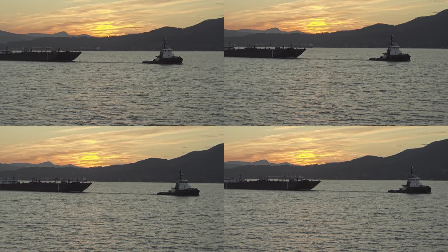 日落时拖着大船的小船