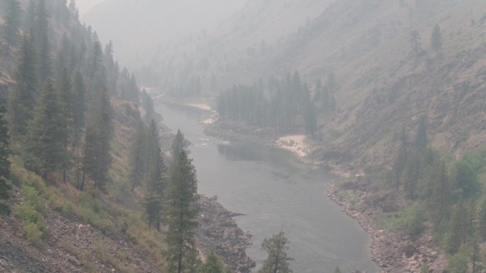 空中俯瞰烟雾弥漫的森林峡谷和河流的下降和倾斜