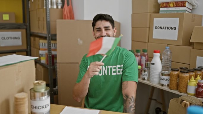 在慈善中心，年轻的西班牙裔志愿者面带微笑，自信地举着意大利国旗