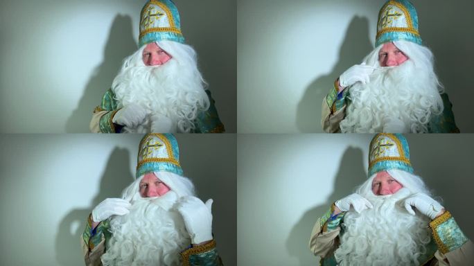 圣尼古拉斯目不转睛地盯着他的胡子，他的胡子疑惑地看着镜头上白色背景上的影子，神奇的工人尼古拉斯，圣诞