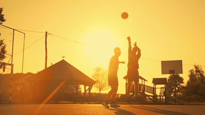 SLO MO男性朋友在日落的橙色天空下与一个跳投一起打篮球