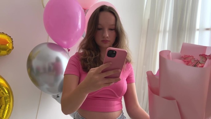 十几岁的女孩庆祝生日15周年气球花白色墙上的数字在互联网上为社交网络拍照假期装饰房间装饰牛仔裤粉红色