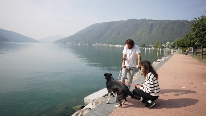 一名拄着拐杖的男子与他的伴侣和他们的狗沿着湖上的木板路散步