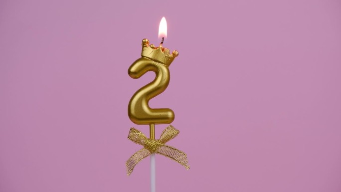 金色生日蜡烛燃烧在粉色，2号。