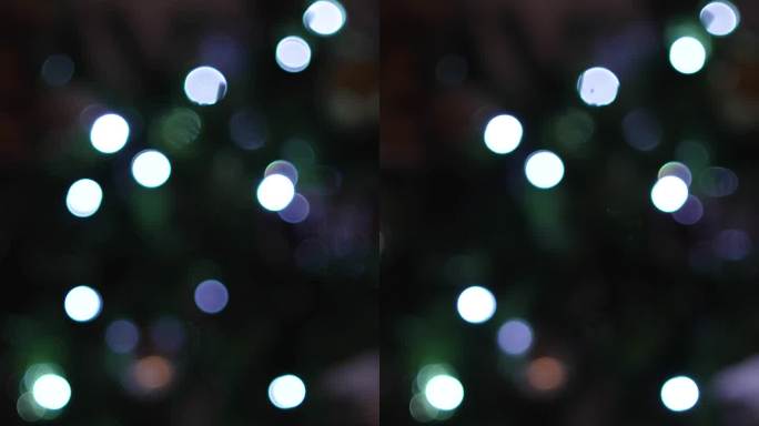 圣诞树上的彩灯亮着，闪闪发光。我看到的视频是一个家庭里的冷杉树上的圣诞灯的失焦视频。