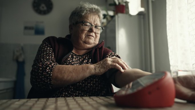SLO MO老年妇女在家用数字测量仪测量血压