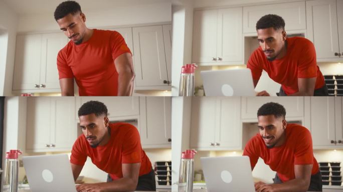 穿着健身服在家里厨房拿着一瓶水在笔记本电脑上工作的男人