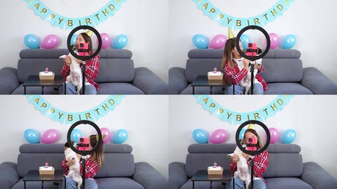 一个十几岁的女孩带着她有趣的宠物狗庆祝她的生日，并在家里拍了一段视频。Z世代达人玩视频自拍拍秀app