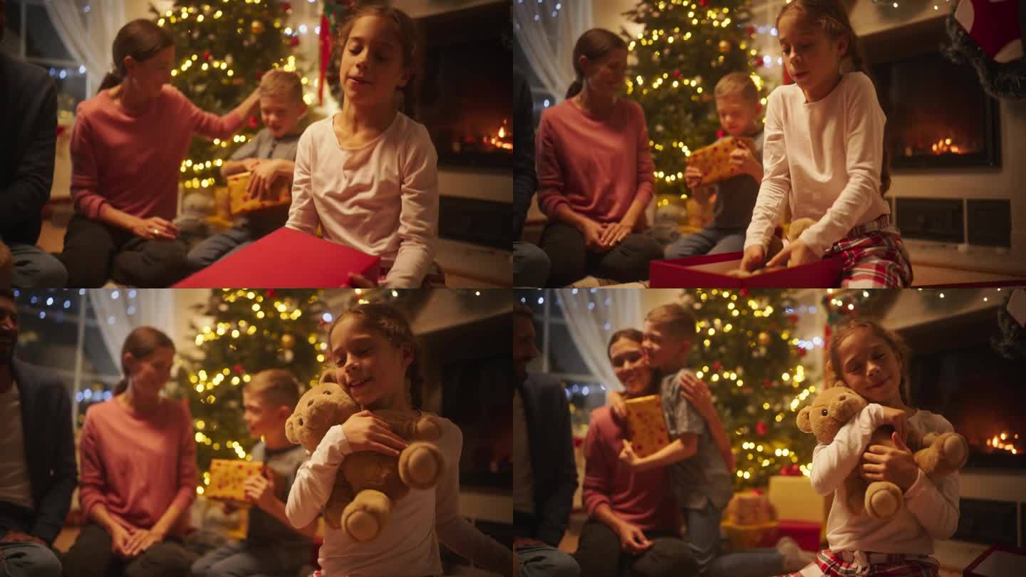 慈爱的年轻父母在平安夜给孩子送礼物的中速慢镜头。惊喜的小女孩收到一个新的泰迪熊毛绒假期