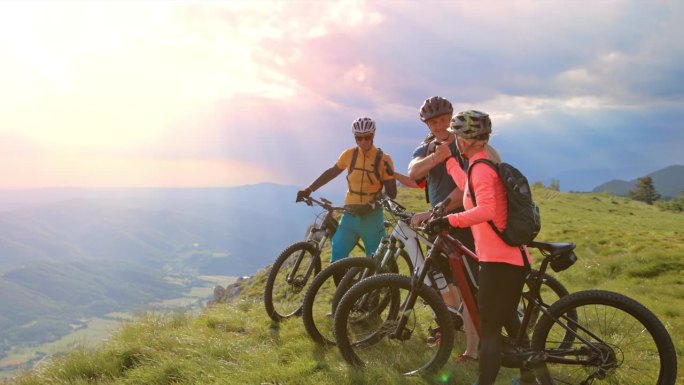一群山地自行车手在阳光下站在山顶上