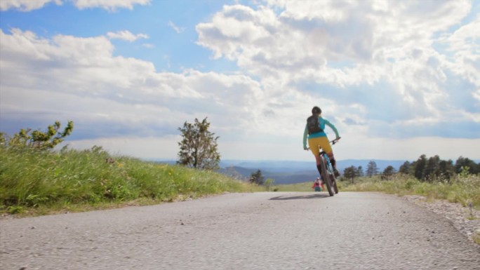 两个女山地自行车手在阳光明媚的山路上疾驰而下