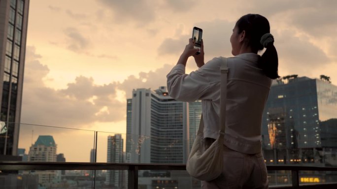 亚洲女性在曼谷市中心游览泰国，欣赏日落时的摩天大楼。