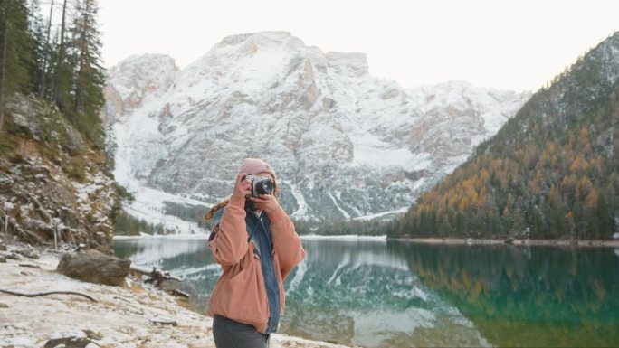 冬日里，拿着相机的女子站在布雷斯湖的背景上