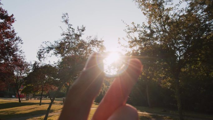 POV在夏天的公园里看着一枚订婚戒指，背景是夕阳。求婚。婚姻和家庭的概念。一个男人手里的结婚戒指。