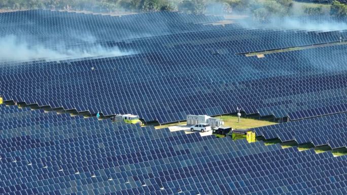 大型可持续发电厂的鸟瞰图，该发电厂有许多排太阳能光伏板，用于生产清洁电能。关键基础设施发生季节性野火