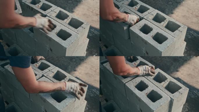 一个无法辨认的男性杂工在建筑工地铺设煤渣砖。艰苦的非技术劳动