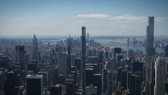 阳光明媚的纽约，从空中俯瞰中央公园和曼哈顿中城的摩天大楼。电影无人机视角的城市天际线与略多云的蓝天