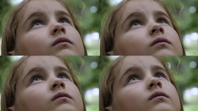 孩子仰望大自然的天空。肖像小女孩祈祷仰望天空与希望和信念，沉思的孩子的脸，特写。女孩仰望上帝的信徒祈