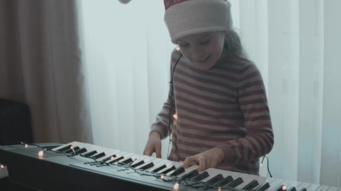 小女孩在家里的圣诞晚会上弹奏电子琴。变形镜头光晕。