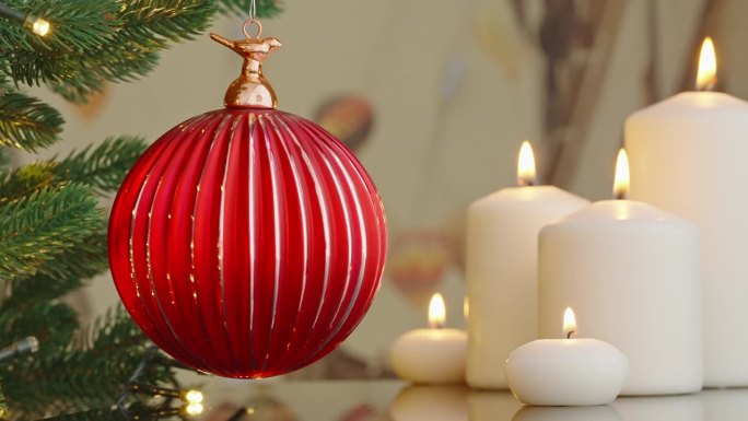 圣诞树树枝上的红色玻璃球特写装饰着燃烧的蜡烛散景，闪烁的灯泡背景上的花环。圣诞节的概念。庆祝新年快乐