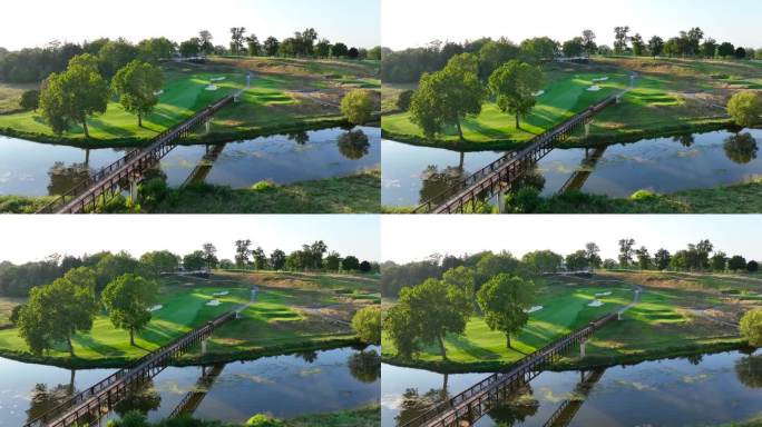 美国阳光明媚的高尔夫球场，以宁静的河流上的木桥、邻近的绿色球道和成熟的树木为特色。日落时高尔夫球车过