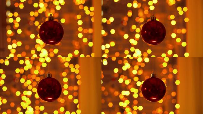 前景是一个红色的圣诞球，背景是闪烁的圣诞灯的美丽散景