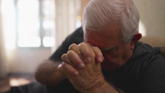 有希望的老人独自在家祈祷。忠诚的白人老年男性，双手紧握，有信仰
