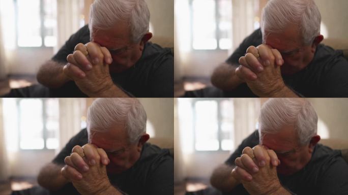 有希望的老人独自在家祈祷。忠诚的白人老年男性，双手紧握，有信仰
