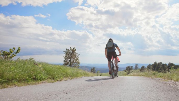 一群山地自行车手在阳光明媚的山路上骑行