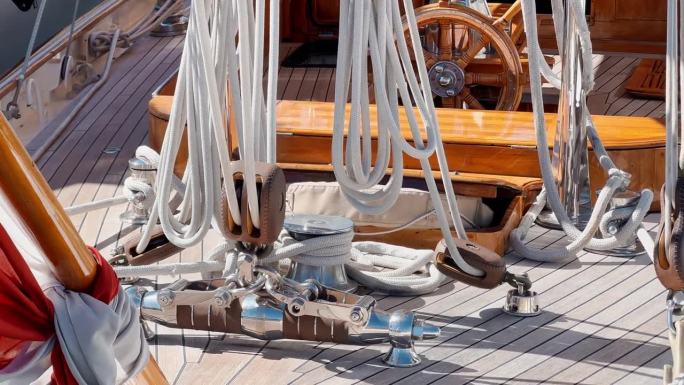 古色古味的护卫舰在阳光明媚的日子里的装备，木制的方向盘，许多绳索，木制的甲板，船在波浪上的岩石，旗帜