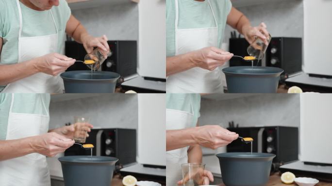 一个穿白围裙的女人把蛋清和蛋黄分开倒进碗里。这个场景是用慢镜头拍摄的。