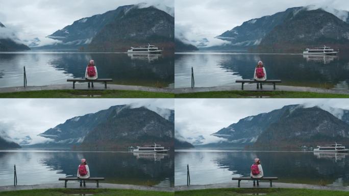 秋天，一个女人坐在长凳上看着哈尔斯塔特湖