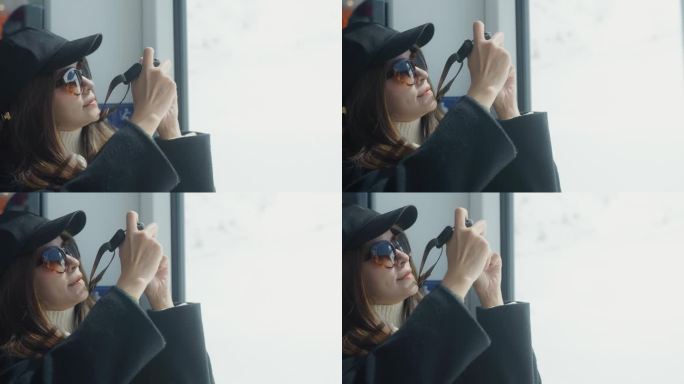 年轻的亚洲女子在寒假乘火车旅行时用数码相机在雪山上拍照。