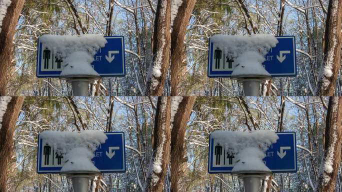 初冬雪后树木公厕卫生间指示牌覆盖冰雪