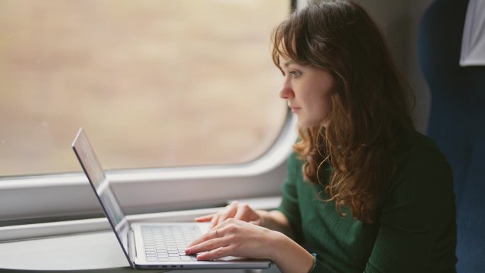 坐火车旅行时用笔记本电脑工作的女人