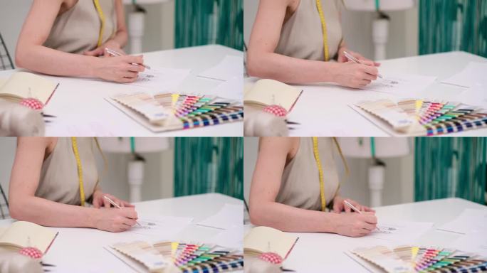 有纹身的女裁缝在时装工作室的桌子上把衣服模型画在纸上