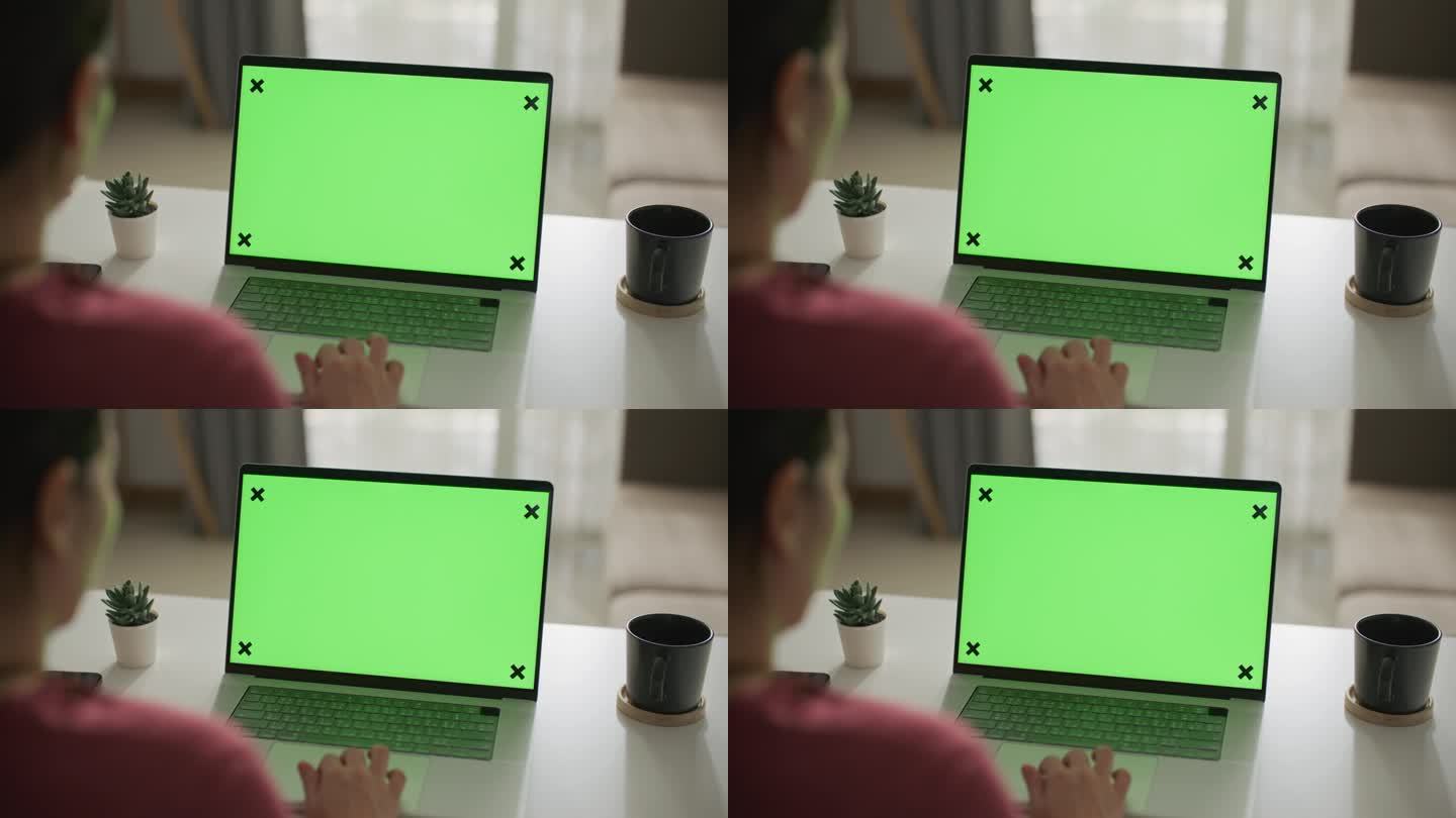 女性在家里使用绿屏空白的笔记本电脑