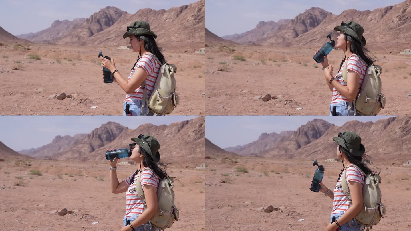 亚洲年轻女子在埃及西奈沙漠行走时喝水