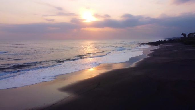 空中4K无人机镜头:迷人的日落在塞塞海滩，巴厘岛;海浪拥抱海岸线，棕榈树在暮色中摇曳;非常适合冥想、