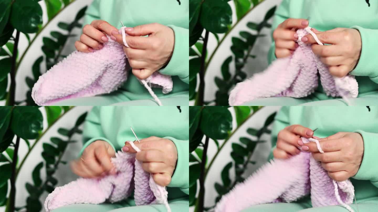 女人的手正在用纱线编织手工羊毛衣服的特写。针线活的概念。爱好的概念
