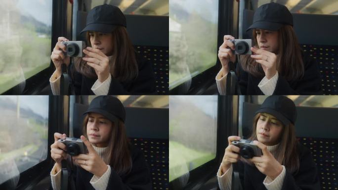 亚洲女游客在瑞士乘火车旅行时，从车窗拿起相机拍照。