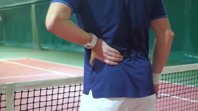 一个年轻人在硬地网球比赛中腰背部受伤。